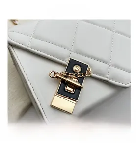 Close-up of golden S-logo clasp and quilted texture on white leather shoulder bag