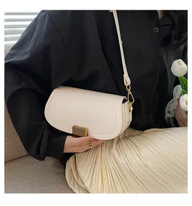 Close-up of cream crossbody bag featuring a golden vertical stripe metal clasp and leather texture