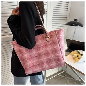 Detail of pink and white checkered tote bag with gold chain strap on model's shoulder