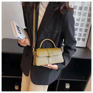 Close-up of olive green crossbody bag with top handle and gold hardware on model