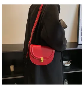 Model wearing a red PU leather saddle bag with gold buckle on a black wool coat