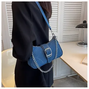 Dettaglio della borsa a tracolla in denim blu con fibbia argentata e catena su modella