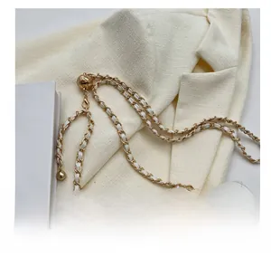 Detailed macro shot of a white quilted leather bag with a gold metal chain and sphere charm