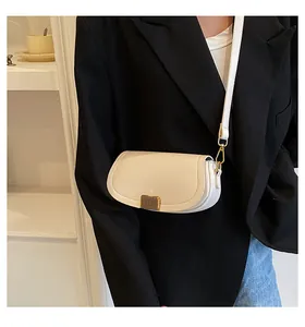 Chic cream saddle bag with gold buckle worn with black blazer and casual jeans