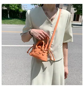 Detail view of mini orange drawstring crossbody bag with Fashion & Bags logo engraving