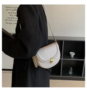 Detailed side view of white saddle bag with gold metal buckle on female model