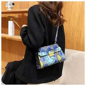 Detail of colorful snakeskin pattern bag with golden square lock on black jacket