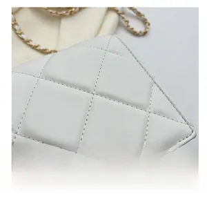 Detail of precise stitching on white quilted leather bag with elegant metal clasp