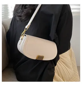 Chic cream saddle bag with gold buckle and adjustable strap shown on model's shoulder