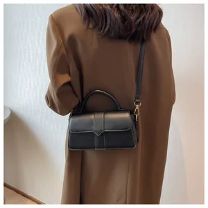 Classic black leather crossbody bag styled with a brown blazer on model for commute