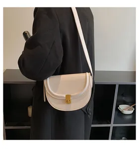 Close-up of a white saddle bag with golden metal buckle on a black coat outfit