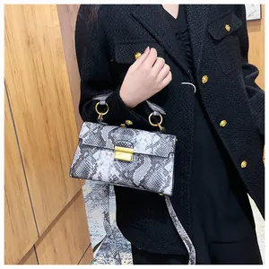Detailed view of the luxury snakeskin pattern texture and gold buckle on a crossbody bag