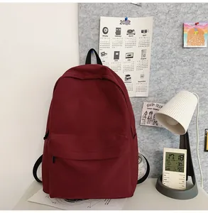 Detail of burgundy canvas backpack with front pocket and side slots in a study setting