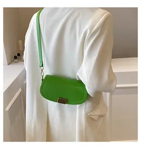 Detail of bright green leather saddle bag with gold metal buckle on white blazer