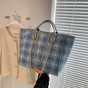 Blue tweed plaid tote bag with silver leather handles and gold chain strap in room setting