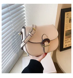 Detail of a vintage saddle bag in cream beige with a wooden buckle and leather strap