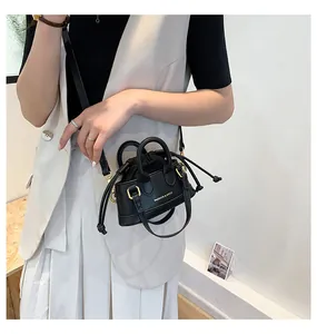 Detail of a mini black crossbody bag with drawstring closure and golden hardware