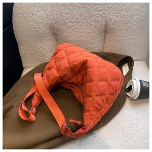 Detail der orangefarbenen Stepptasche mit gelber Kontrastnaht und Halbmond-Form