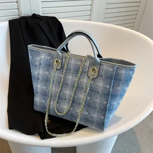 Large blue denim geometric tote bag with leather straps and chain shoulder strap