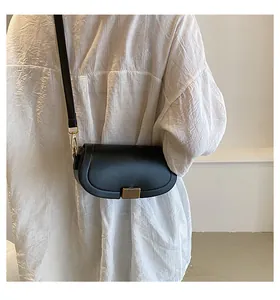 Detail of a minimalist black leather saddle bag with gold vertical stripe metal clasp