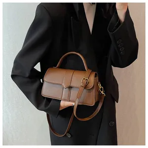 Detail of caramel faux leather bag featuring golden buckles and adjustable shoulder strap