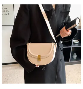 Detail of beige faux leather saddle bag with gold buckle worn on a black wool coat