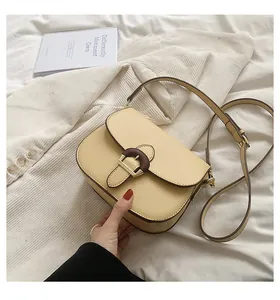 Detail of beige saddle bag with wood texture buckle and dual straps on white blazer