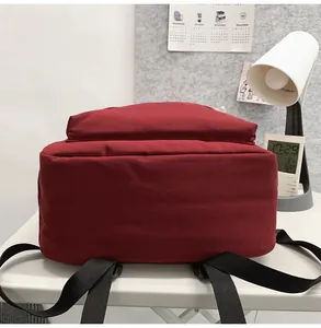 Side view of dark red canvas backpack showing adjustable black straps and spacious bottom