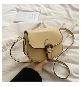 Detail of cream saddle bag featuring unique brown wood grain buckle and metal hardware
