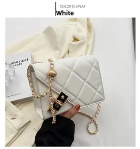 Close-up of white quilted crossbody bag with gold chain strap and metal ball detail