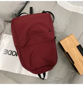 Detailed top view of a minimalist burgundy backpack with fabric texture and front zipper