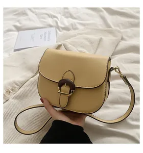 Detail of yellow leather saddle bag featuring a unique wooden ring buckle and gold hardware