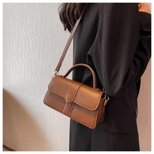 Detail view of vintage brown PU leather bag with gold hardware and flap closure