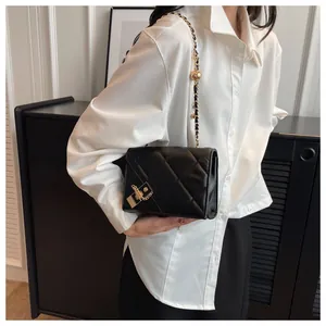 Close-up of quilted black leather shoulder bag with golden lock and chain strap