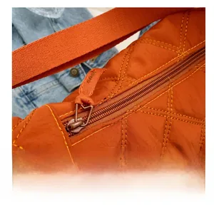 Detail der orangefarbenen gesteppten Umhängetasche mit Reißverschluss und Rautenmuster