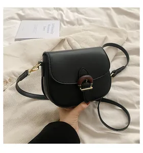 Detailed close-up of a black vintage saddle bag with unique wood-grain textured buckle clasp
