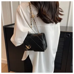 Close-up of black quilted shoulder bag with gold chain strap and metal clasp detail