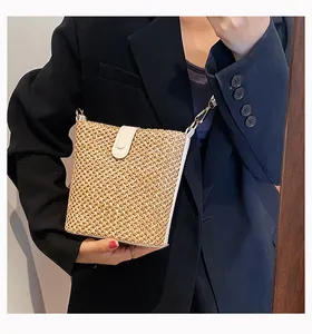 Detail of straw woven crossbody bag with white leather flap and gold metal buckle