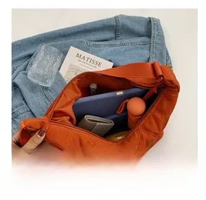 Detailaufnahme der geräumigen orangefarbenen Stepptasche mit Tablet und Alltagsgegenständen