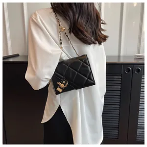Close-up of black quilted leather crossbody bag with gold chain strap and metal lock