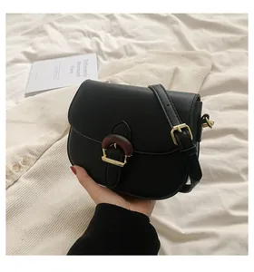 Detail of a black saddle bag featuring a unique gold metal and wood texture buckle closure