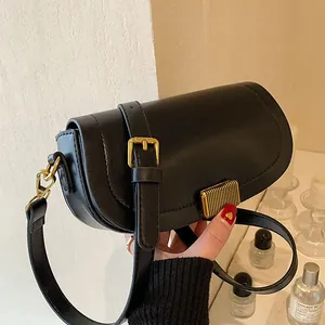 Modern black half-moon saddle bag with gold metal buckle and adjustable shoulder strap