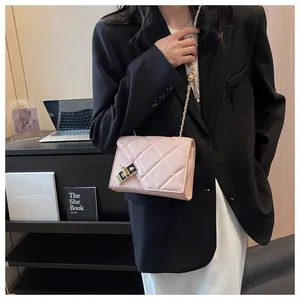 Detail view of light pink quilted square crossbody bag with gold-tone hardware and chain strap