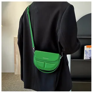 Detailansicht einer hellgrünen Satteltasche mit Silberschrift auf einem schwarzen Blazer