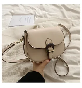 Close-up of cream saddle bag with retro wood buckle and gold metal hardware detail