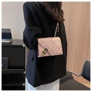 Macro detail of pink quilted shoulder bag with gold chain strap and metal lock closure