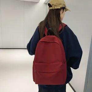 Minimalist red nylon backpack with large capacity worn by model in a modern indoor setting