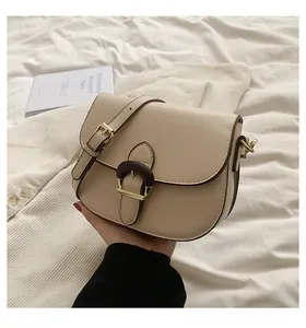 Detail of cream saddle bag featuring wood texture buckle and gold metal hardware
