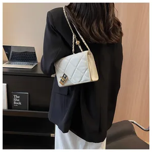 Close-up of beige quilted crossbody bag with gold chain strap and turn-lock hardware