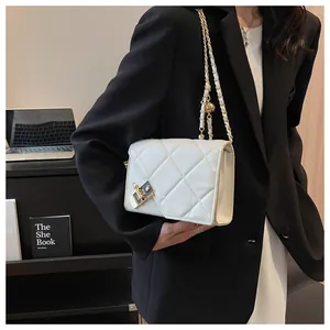 Close-up of white quilted leather bag with gold chain strap and metal lock detail
